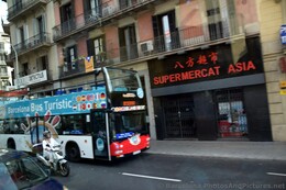 Spanish Woman on Scooter in Barcelona Passing Chinese Market.jpg